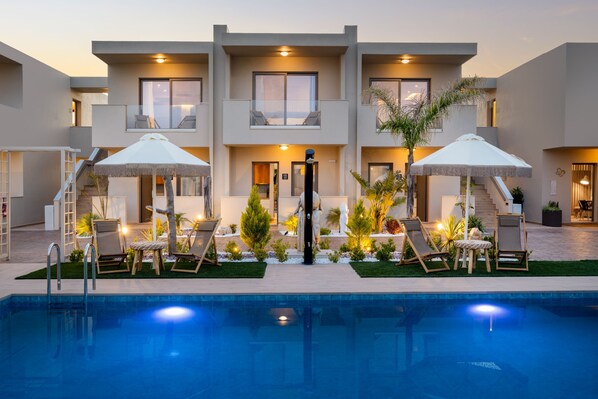 Een modern hotel met een zwembad, ligbedden en parasols.