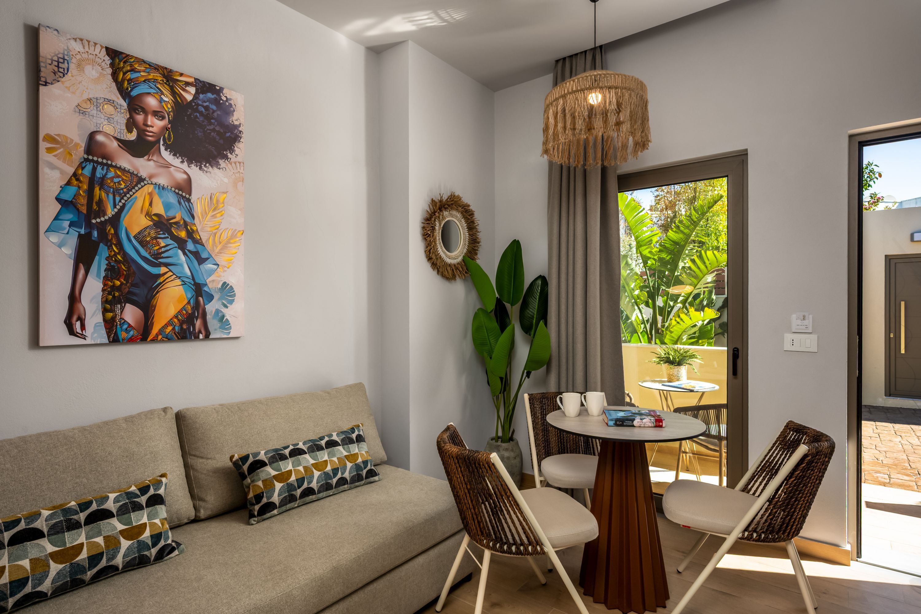 A modern living room with a sofa, two chairs, a round table, and a painting on the wall.