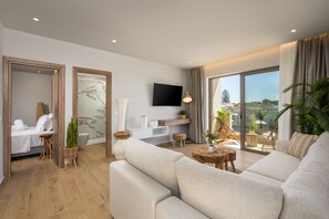 Uma sala de estar moderna com sofá, televisão, varanda com plantas e chão de madeira.