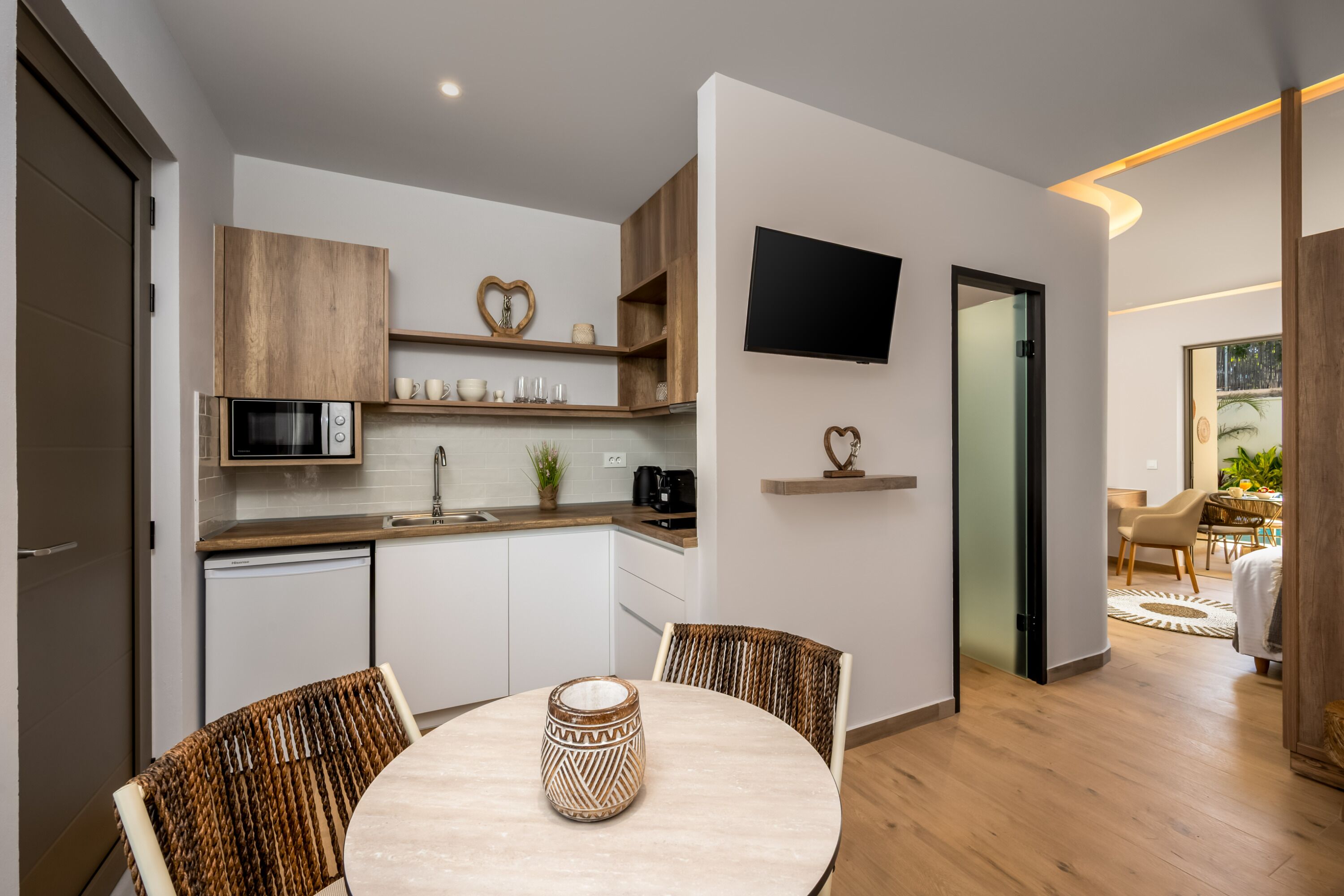 Eine moderne Küche mit Holzausstattung, einer Mikrowelle und einem Essbereich mit rundem Tisch und Stühlen.