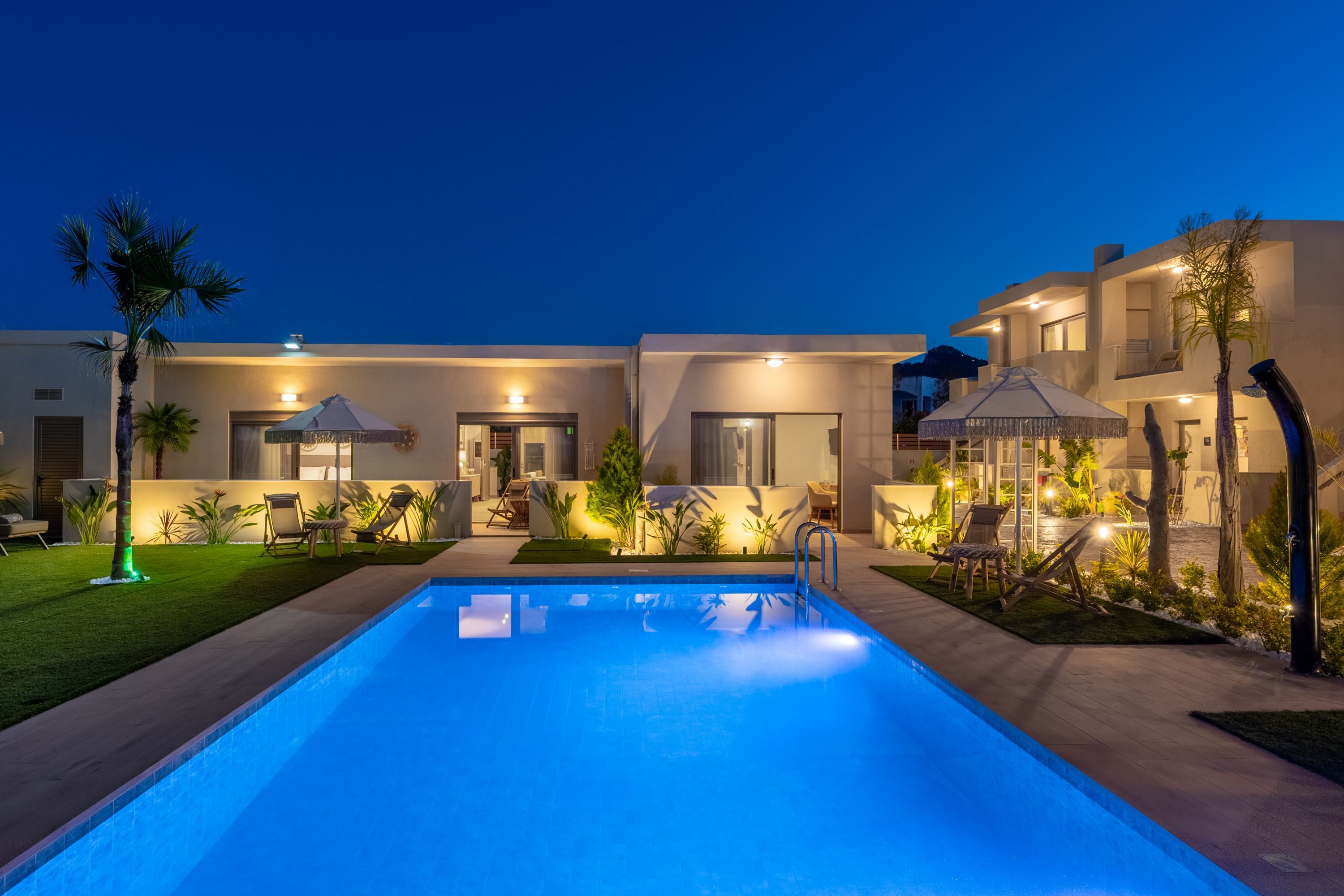 Um hotel moderno com piscina, área de estar externa e caminhos bem iluminados.