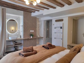 A modern hotel room with a large bed, a round mirror, a built-in sink, and a towel rack. - Tresors de Sens  (Sens)