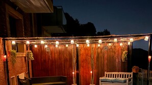 Un jardin avec un jacuzzi, une clôture en bois, des guirlandes lumineuses et du mobilier d’extérieur.
