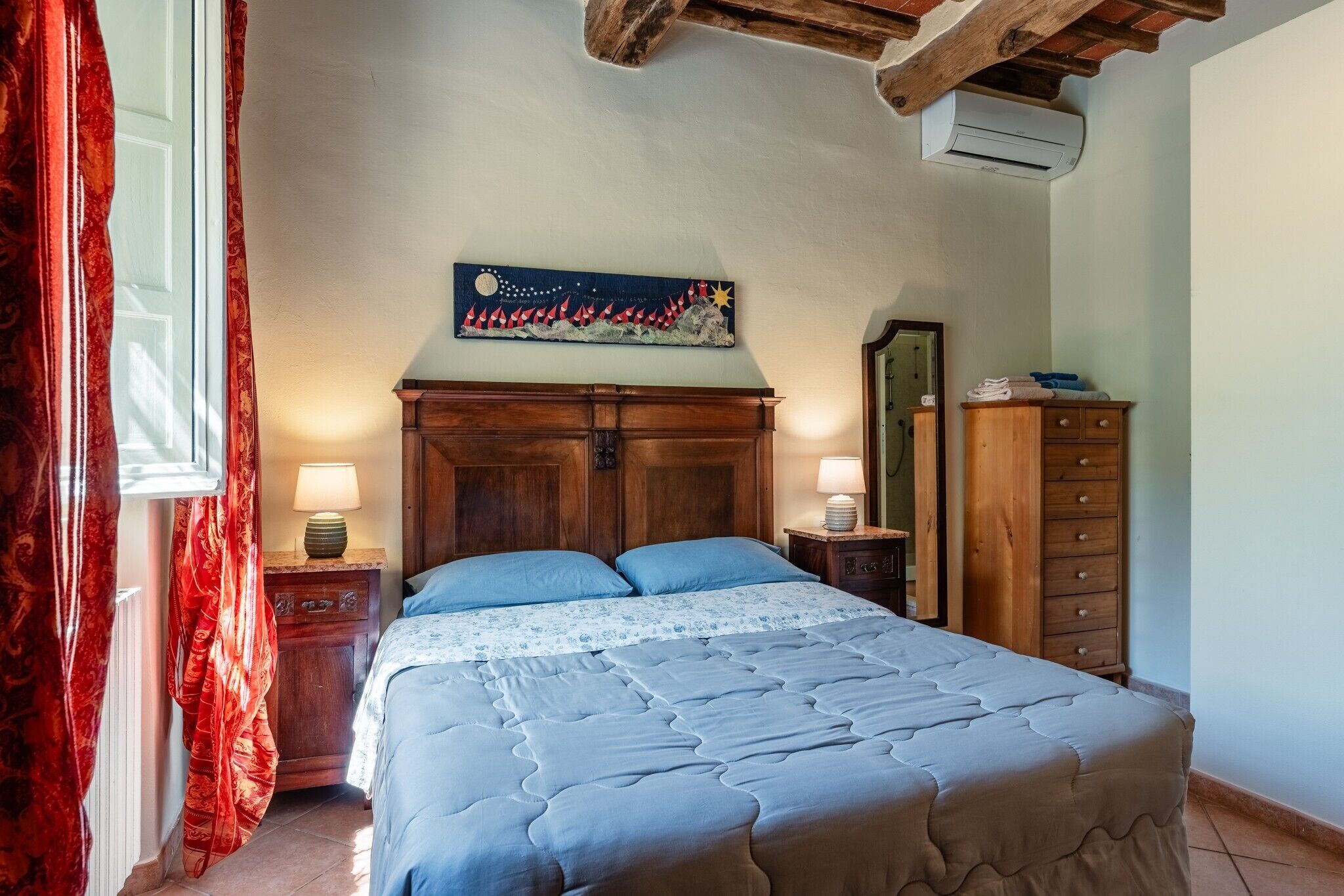 Ein Schlafzimmer mit einem Bett, einem Holz-Kopfteil, Nachttischen, einer Kommode und einem an der Wand befestigten Kunstwerk.