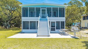 A two-story house with a central staircase, large windows, and a patio area. - Register - A cozy 2-Bedroom Duplex with Soundfront Views for 6 Guests (Surf City)