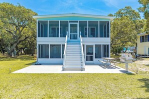 A two-story house with a central staircase, large windows, and a patio area. - Register - A cozy 2-Bedroom Duplex with Soundfront Views for 6 Guests (Surf City)