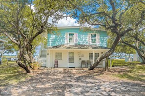 A two-story building with a white exterior and teal shutters, surrounded by trees. - Register - A cozy 2-Bedroom Duplex with Soundfront Views for 6 Guests (Surf City)
