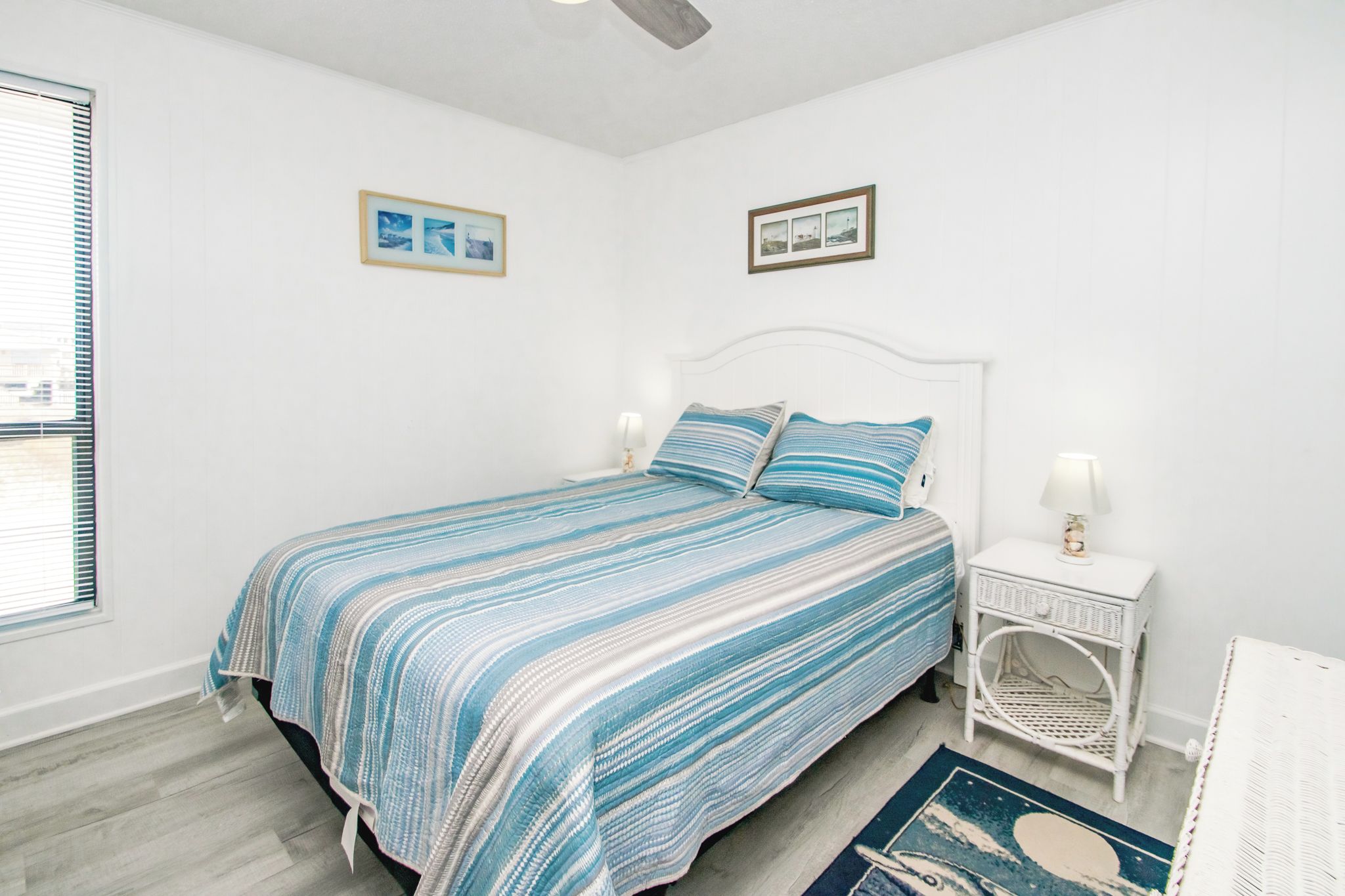 A bedroom with a bed, a nightstand, a lamp, a chair, and two framed pictures on the wall.