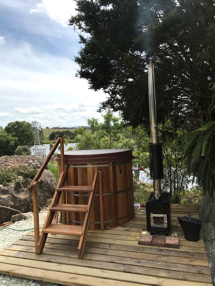 A wooden deck with a hot tub, a wooden ladder, and a wood-burning stove.