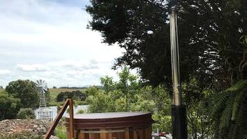 A wooden deck with a hot tub, a wooden ladder, and a wood-burning stove.