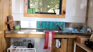 Eine kleine Küche mit Fenster, Spüle und einem kleinen Backofen.