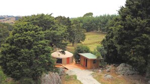 Eine Jurte mit einem Feldweg, der davorhinführt, umgeben von Bäumen und einer hügeligen Landschaft.