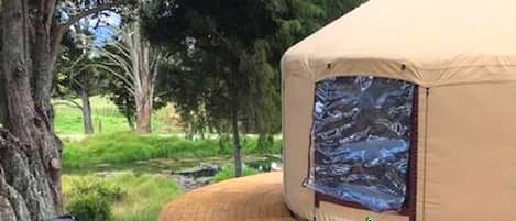 Una carpa con vista a un arroyo rocoso, rodeada de árboles.