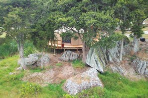A wooden deck with a built-in seating area surrounded by large rocks and trees.