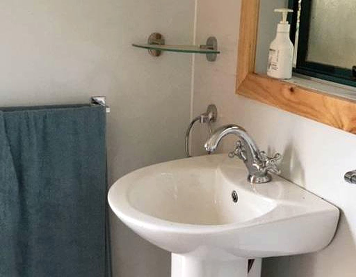 A bathroom with a white sink, a mirror, and a towel rack.