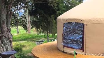 A tent with a view of a rocky stream, surrounded by trees.