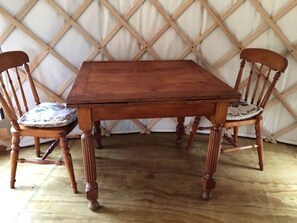 A wooden dining table with four chairs, each with a cushioned seat. - Secluded Yurt Rental Ideal for a Romantic Getaway near Whangarei, North Island (Ruatangata West)