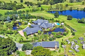A large estate with multiple buildings, a lake, and surrounding greenery.