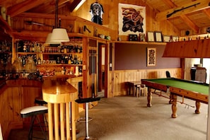 Eine Barbereitschaft mit Holzwänden, einem Billardtisch und einem Snookertisch.