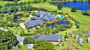 A large estate with multiple buildings, a lake, and surrounding greenery.