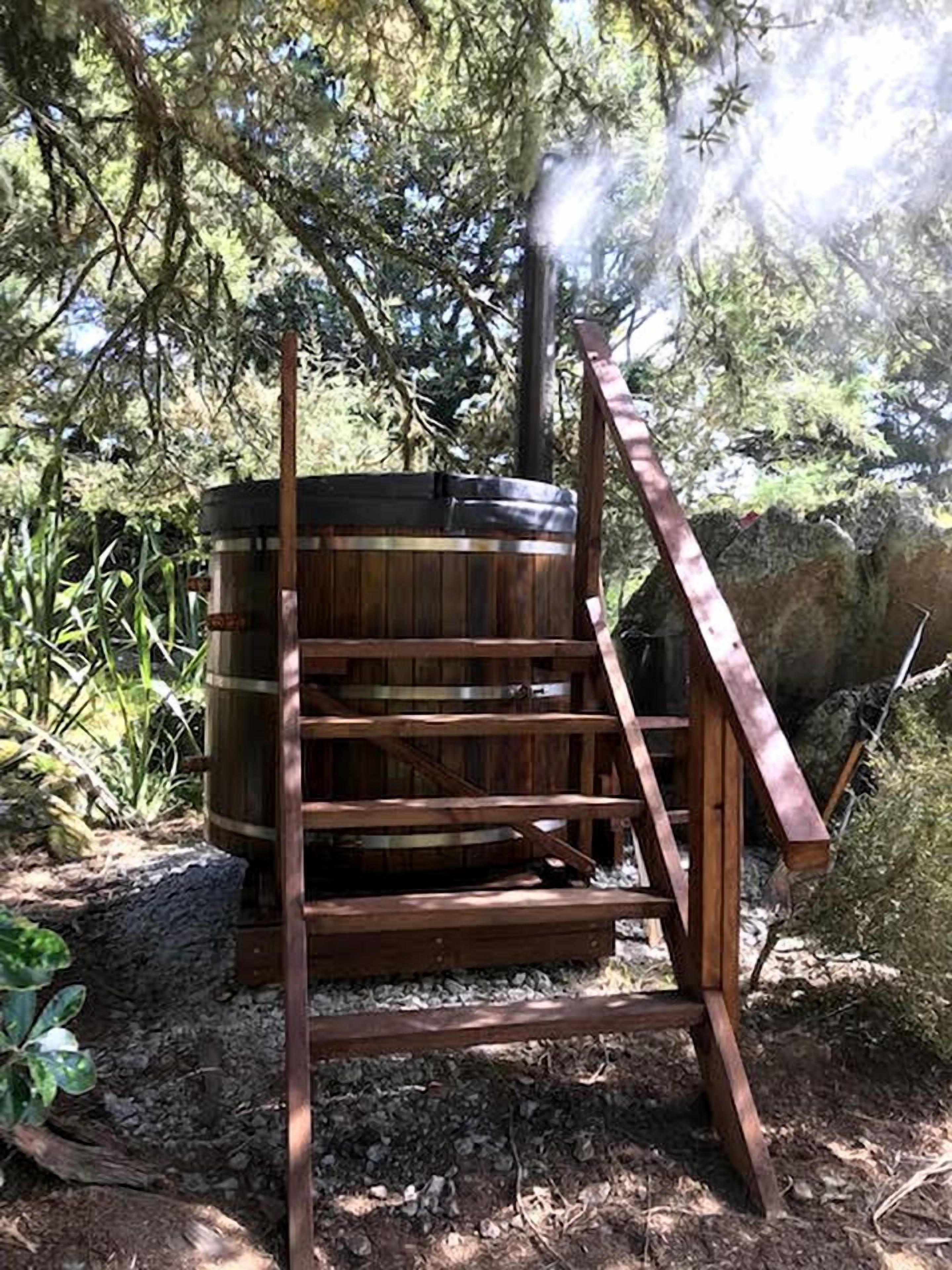 Una estructura de madera con un barril, rodeada de árboles y rocas.