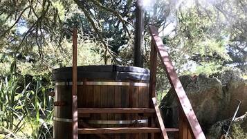 Una estructura de madera con un barril, rodeada de árboles y rocas.