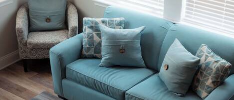 A living room with a teal sofa, patterned armchair, and a coffee table with a map design.