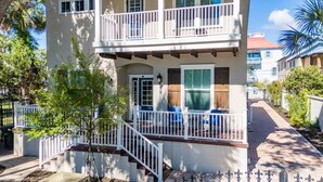 Ein zweistöckiges Gebäude mit Balkon, Eingangstür und einer kleinen Veranda mit Sitzbank.