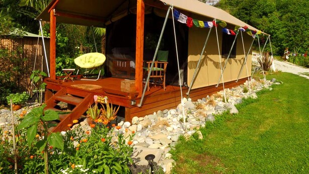 Un hébergement sous tente doté d’une terrasse en bois, d’un espace salon extérieur et d’un jardin.