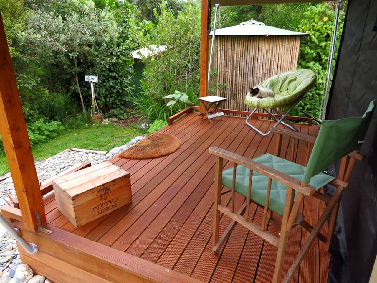 Une terrasse en bois avec une chaise, une petite table et une boîte en bois.