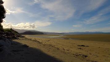 A beach with a clear sky, distant mountains, and a calm sea.
