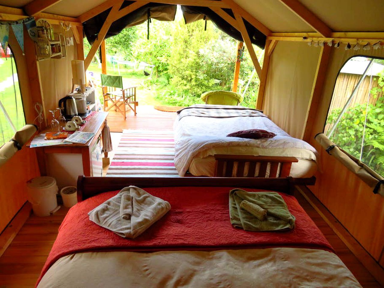 Une chambre confortable aménagée comme une tente, avec un lit, un petit bureau et une chaise.