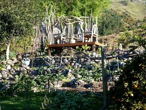 A garden with a stone wall, wooden structures, and various plants. - Glamping Tent on Permaculture Farm near Pohara Beach in Golden Bay, South Island (Pohara)