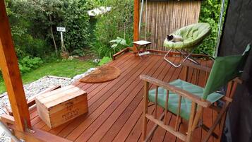 Una terraza de madera con una silla, una mesita y un cofre de madera.