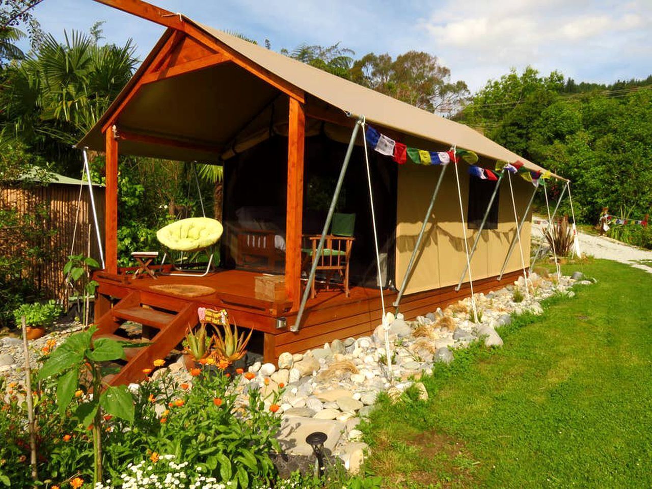 Un allotjament amb tendes, un terra de fusta, seients a l'exterior i una zona de jardí.