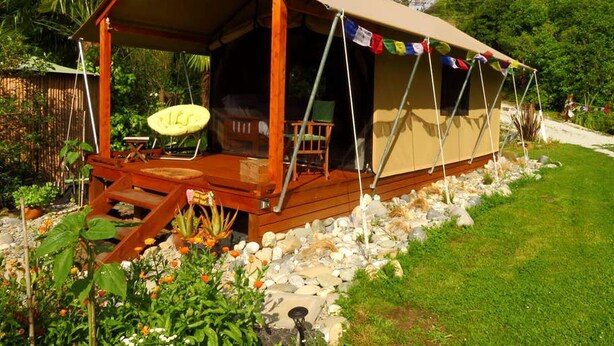 Un hébergement sous tente doté d’une terrasse en bois, d’un espace salon extérieur et d’un jardin.