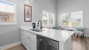 A modern kitchen with a central island, white cabinetry, and a built-in dishwasher. - Villa Mojito Unit B in Historic Downtown (St. Augustine)