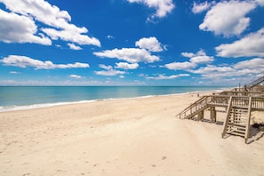 A beach with a wooden staircase leading to a wooden structure, overlooking a clear blue sea. - Sea-Renity Oceanfront 4 bedroom, 2 bath home in Surf City! (Surf City)
