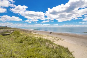 Une plage avec une promenade en bois, un rivage sablonneux et un ciel dégagé.