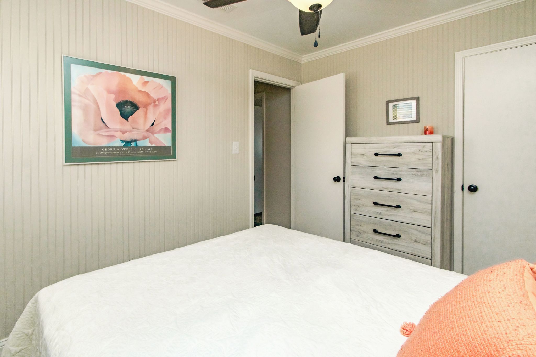 A bedroom with a bed, a dresser, and a poster on the wall.