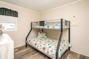 A bunk bed with a floral bedspread, a small bedside table, and a window with blinds. - Sea-Renity Oceanfront 4 bedroom, 2 bath home in Surf City! (Surf City)