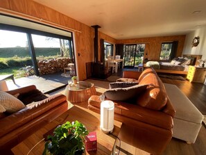 Un salon moderne doté d’une grande fenêtre, d’une cheminée et d’un coin salon confortable.