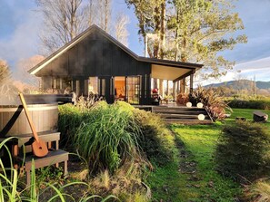 Una casa moderna con un porche cubierto, un jacuzzi y una terraza de madera.