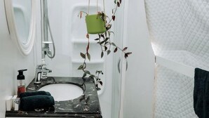 A bathroom with a white sink, mirror, and shower.