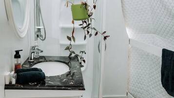Une salle de bain avec un lavabo blanc, un miroir et une douche.