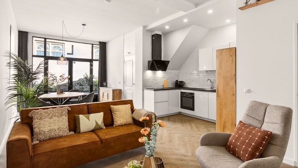 A modern living room with a sofa, armchair, and a dining area with a table and chairs. - Amstel l Family friendly l Fully equipped l Unit L (Amsterdam)