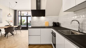 A modern kitchen with white cabinets, a black countertop, and a stainless steel sink. - Amstel l Family friendly l Fully equipped l Unit L (Amsterdam)