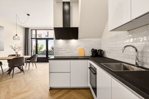 Een moderne keuken met witte kasten, een zwart aanrecht en een roestvrijstalen spoelbak.