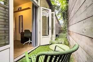 Une terrasse avec une table et des chaises, une porte donnant sur un espace intérieur et une clÎture en bois.