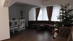 Una sala de estar con un sofá, una mesa de centro, un comedor con sillas y un árbol de Navidad.